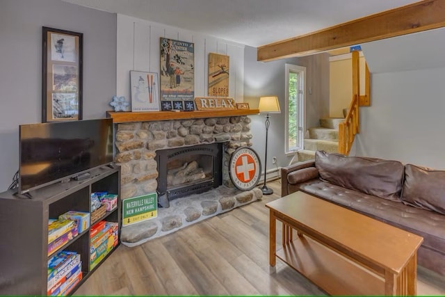 living room with a fireplace, beamed ceiling, wood finished floors, and stairs