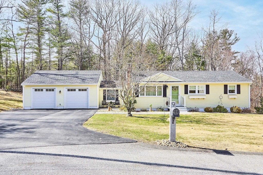 single story home featuring driveway, a garage, and a front lawn
