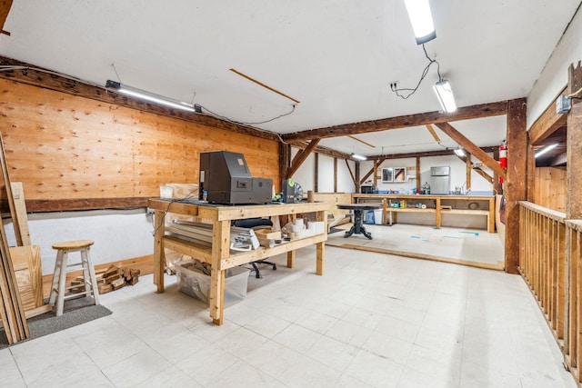 below grade area featuring tile patterned floors, wood walls, and a workshop area
