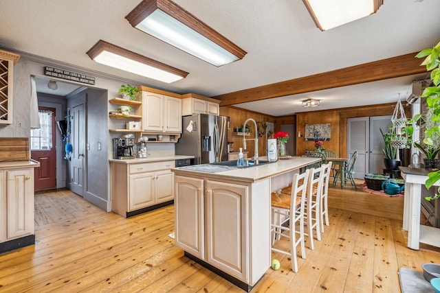 kitchen with light wood-type flooring, light countertops, open shelves, and stainless steel fridge