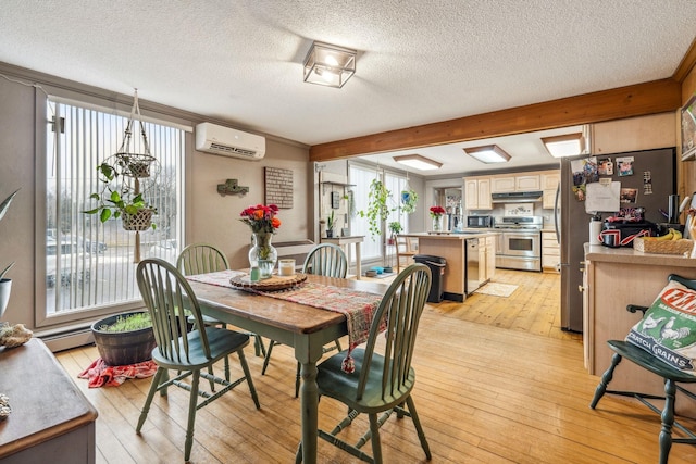 dining area featuring a wall mounted air conditioner, light wood-style floors, a textured ceiling, and beam ceiling