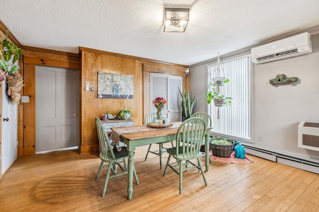 dining room with a wall mounted AC, a baseboard radiator, hardwood / wood-style floors, and a textured ceiling