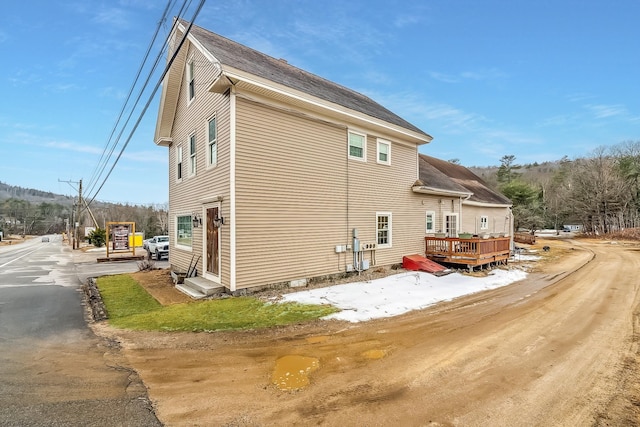 view of side of home with a shingled roof and a deck