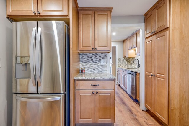 114 Winterwood Dr Unit 114, Londonderry, NH 03053 - kitchen with tasteful backsplash, a sink, light wood finished floors, light stone countertops, and stainless steel appliances