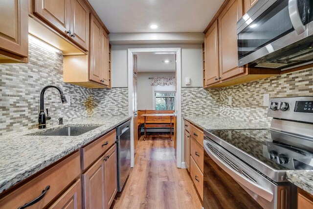 114 Winterwood Dr Unit 114, Londonderry, NH 03053 - kitchen with light wood-style floors, light stone countertops, a sink, stainless steel appliances, and decorative backsplash
