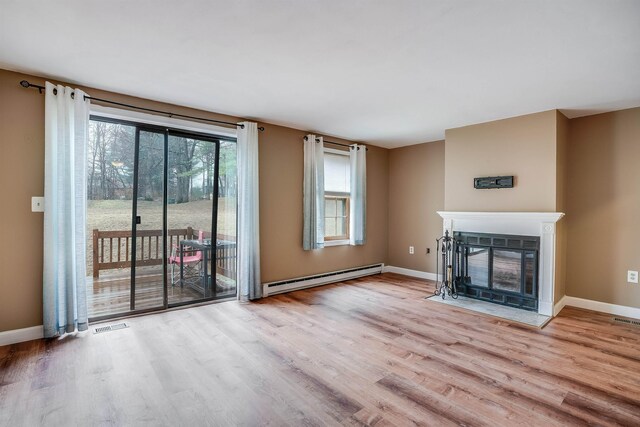 114 Winterwood Dr Unit 114, Londonderry, NH 03053 - unfurnished living room featuring baseboards, a fireplace with flush hearth, visible vents, a baseboard radiator, and wood finished floors