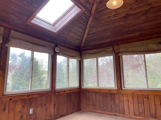 unfurnished sunroom with a skylight, plenty of natural light, wood walls, and vaulted ceiling