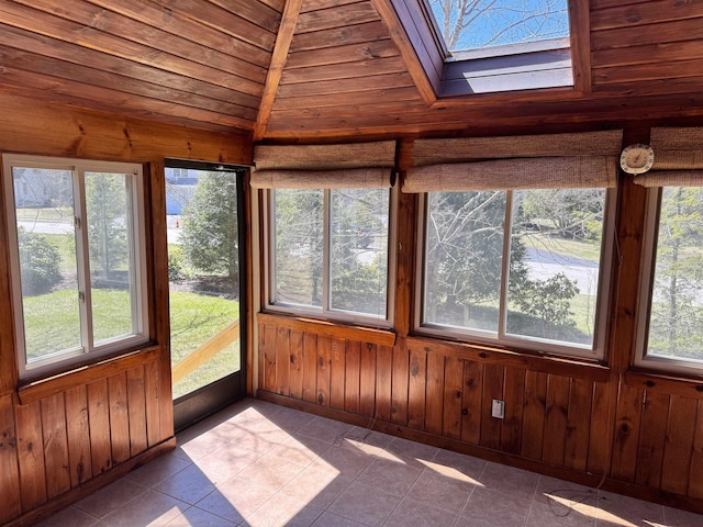 unfurnished sunroom with a skylight, healthy amount of natural light, wooden walls, wooden ceiling, and tile patterned flooring