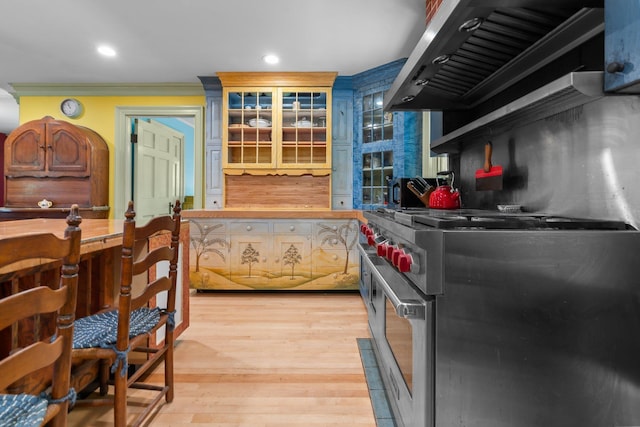 kitchen with exhaust hood, crown molding, recessed lighting, light wood finished floors, and high end stainless steel range