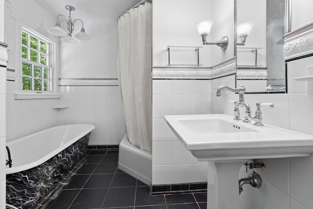 bathroom with tile walls, a bath, wainscoting, and tile patterned floors