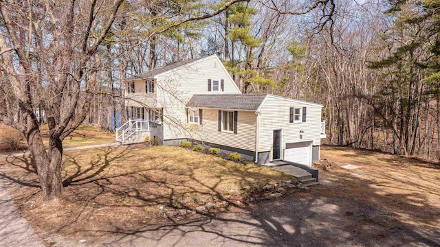 view of front of property with dirt driveway, a shingled roof, and a garage