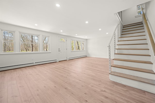 interior space with wood finished floors, a baseboard heating unit, recessed lighting, and stairway