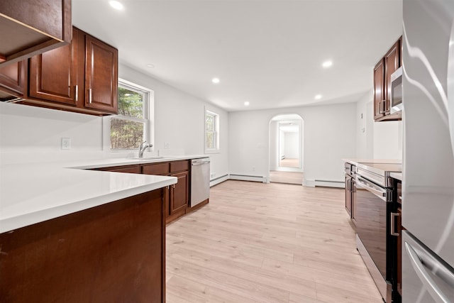 kitchen featuring arched walkways, light wood-type flooring, recessed lighting, a sink, and stainless steel appliances