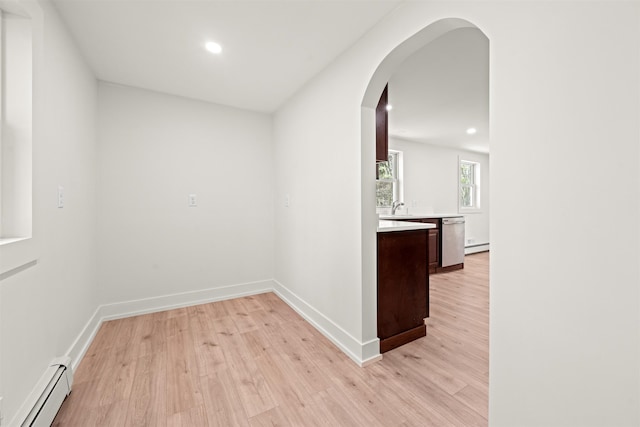 interior space with a baseboard radiator, light wood-type flooring, arched walkways, and recessed lighting