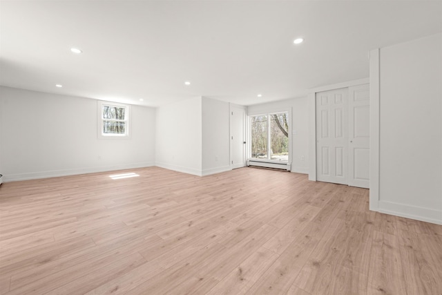 empty room with a baseboard radiator, a healthy amount of sunlight, recessed lighting, and light wood-style floors