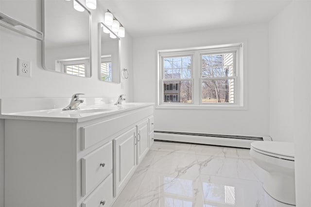 bathroom featuring toilet, marble finish floor, a baseboard heating unit, a sink, and double vanity
