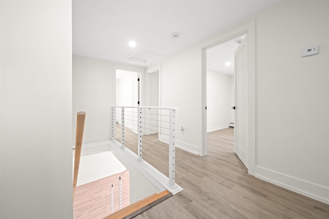 corridor with baseboards, attic access, a baseboard heating unit, and wood finished floors