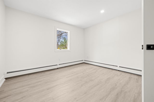 spare room with wood finished floors, a baseboard heating unit, and recessed lighting