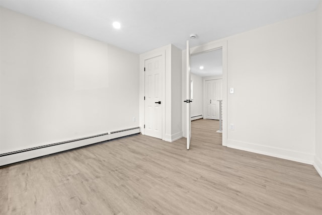 spare room with baseboards, light wood finished floors, and a baseboard heating unit