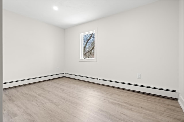 spare room with wood finished floors and a baseboard heating unit