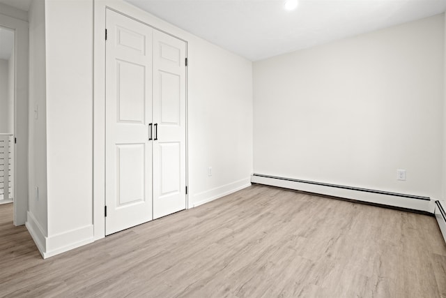 unfurnished bedroom with baseboards, wood finished floors, and baseboard heating