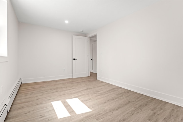 empty room featuring light wood-style flooring, a baseboard radiator, baseboards, and recessed lighting