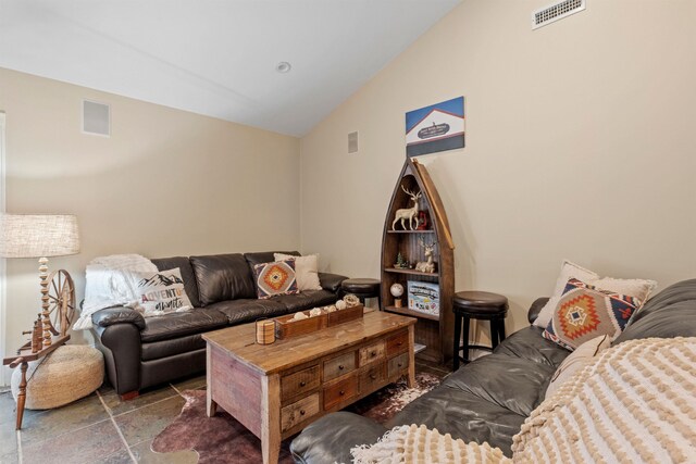 living room with stone tile floors, vaulted ceiling, and visible vents