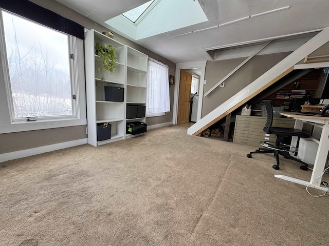 unfurnished office featuring carpet floors, baseboards, and a skylight