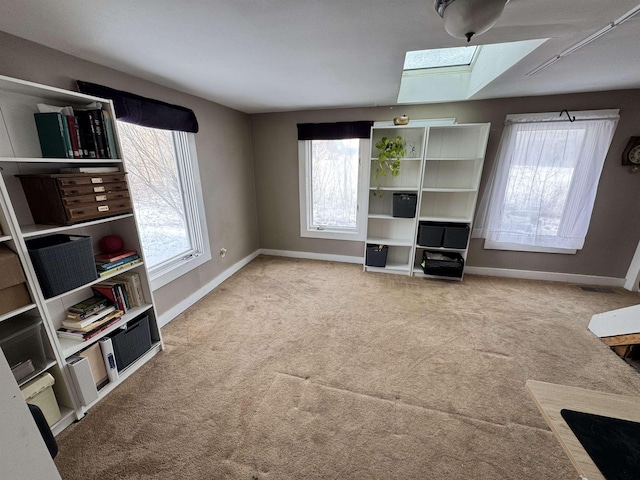 unfurnished living room featuring a healthy amount of sunlight, carpet flooring, and baseboards