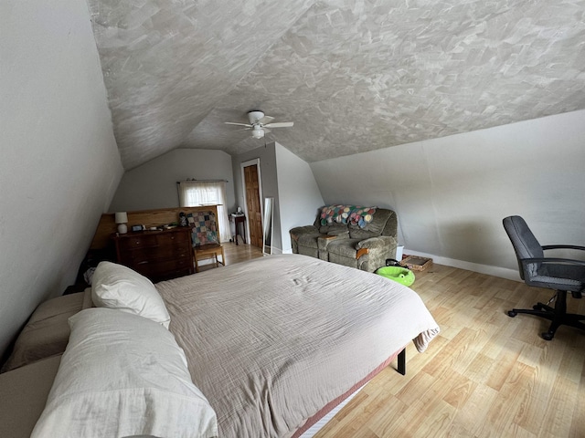 bedroom with a textured ceiling, a ceiling fan, wood finished floors, lofted ceiling, and baseboards