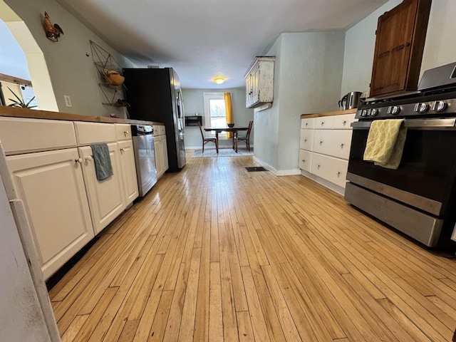 kitchen featuring visible vents, baseboards, light wood-type flooring, appliances with stainless steel finishes, and white cabinetry