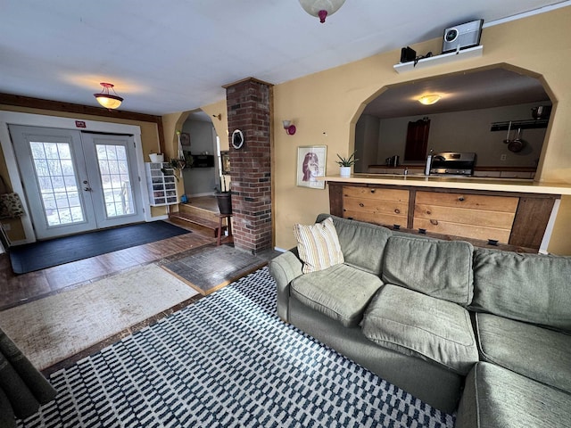 living area featuring arched walkways, french doors, and wood-type flooring