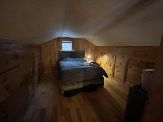 bedroom with wooden walls, wood finished floors, and lofted ceiling