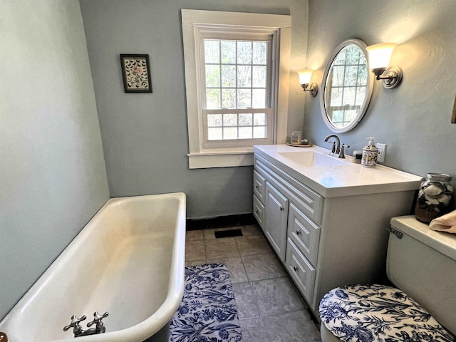 bathroom with baseboards, a bathing tub, toilet, vanity, and tile patterned flooring