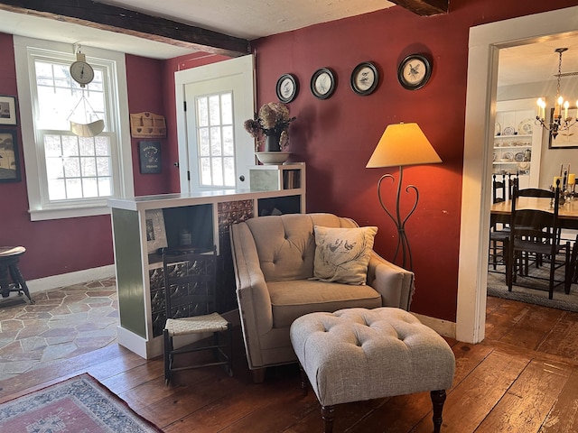 sitting room with beamed ceiling, baseboards, an inviting chandelier, and hardwood / wood-style flooring