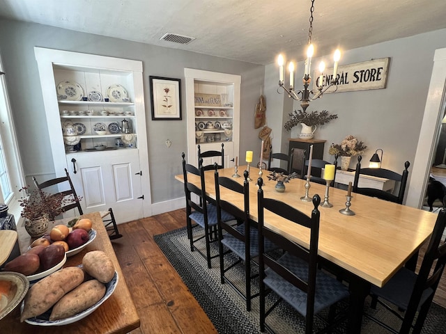 dining room with visible vents, built in features, baseboards, a notable chandelier, and dark wood-style flooring