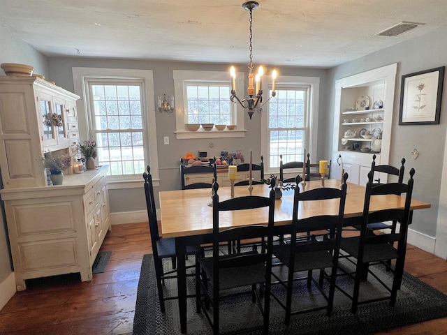 dining space featuring dark wood-style flooring, visible vents, a notable chandelier, and a healthy amount of sunlight