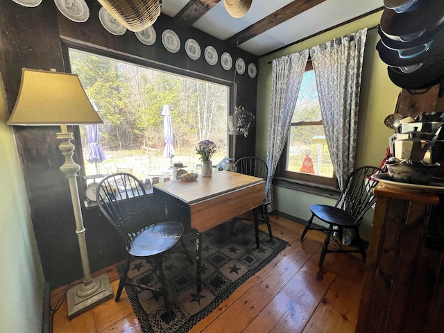 dining room featuring baseboards, hardwood / wood-style floors, and beam ceiling