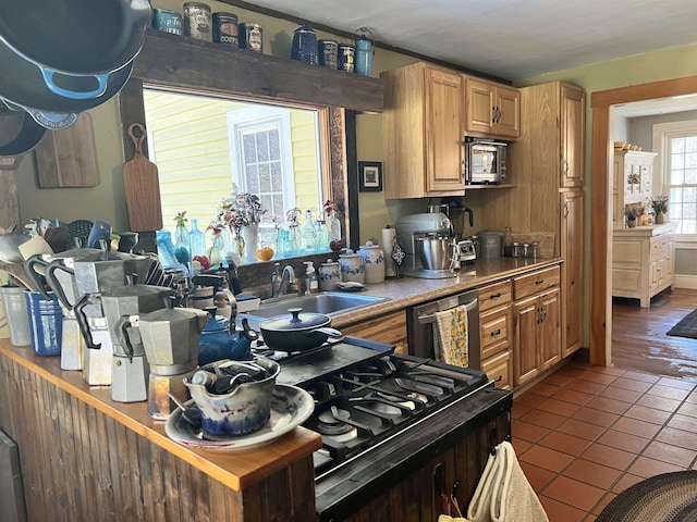 kitchen featuring stainless steel microwave, dark tile patterned floors, light countertops, dishwashing machine, and a sink