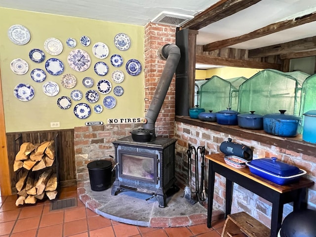 room details with a wood stove, visible vents, beamed ceiling, and wainscoting