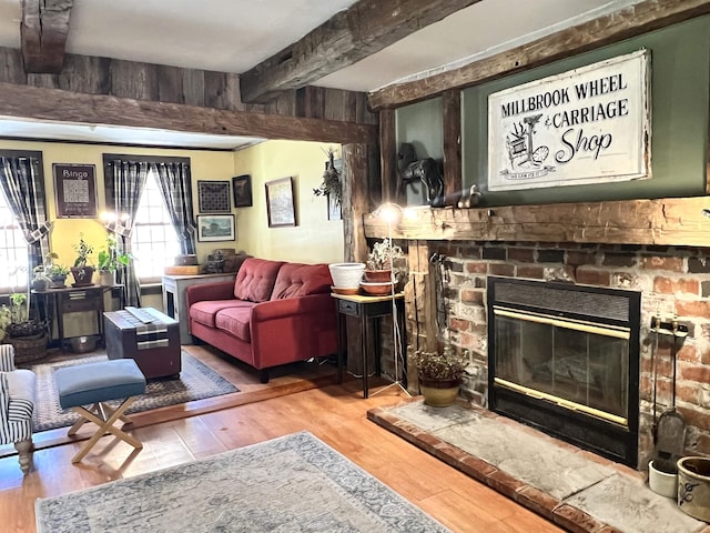 living room with a glass covered fireplace, beamed ceiling, and wood finished floors
