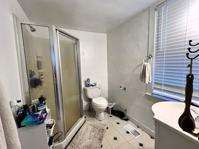 bathroom featuring vanity, toilet, a stall shower, baseboards, and tile patterned floors