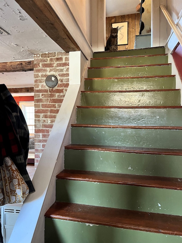 staircase with wooden walls and beamed ceiling