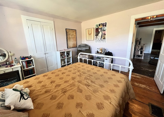 bedroom with a closet, wood finished floors, and visible vents