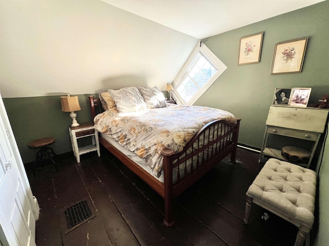 bedroom with wood-type flooring, visible vents, and vaulted ceiling
