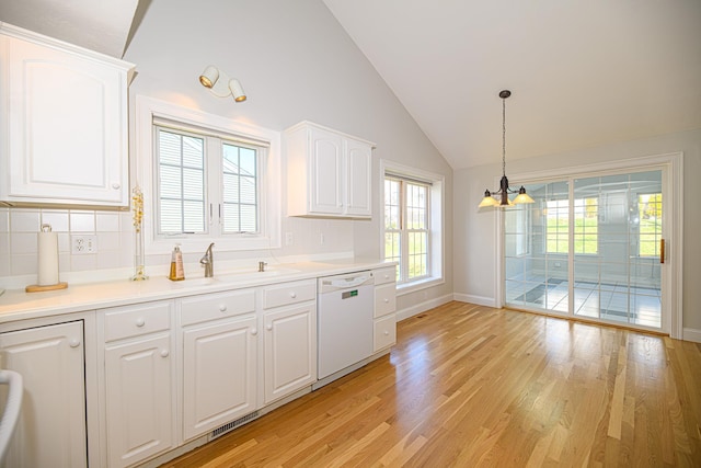 kitchen featuring white dishwasher, vaulted ceiling, a sink, a chandelier, and light wood finished floors
