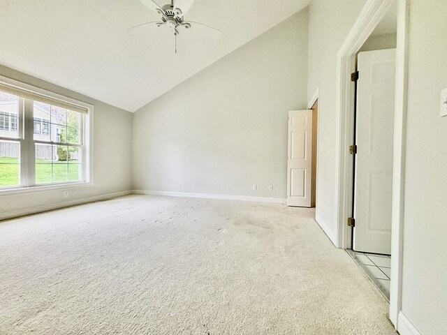 unfurnished room with light carpet, vaulted ceiling, baseboards, and a ceiling fan