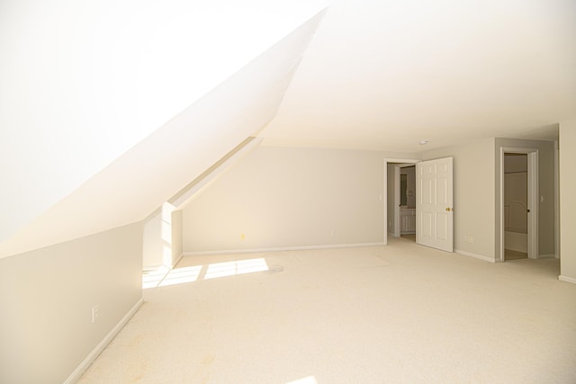 additional living space with light carpet, baseboards, and lofted ceiling