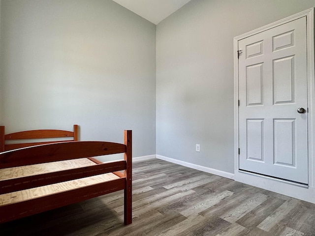 bedroom with baseboards, vaulted ceiling, and wood finished floors