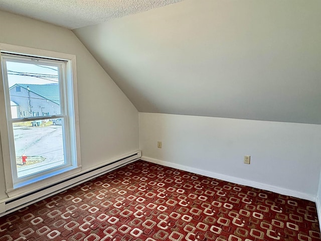 additional living space with baseboards, baseboard heating, a textured ceiling, and vaulted ceiling